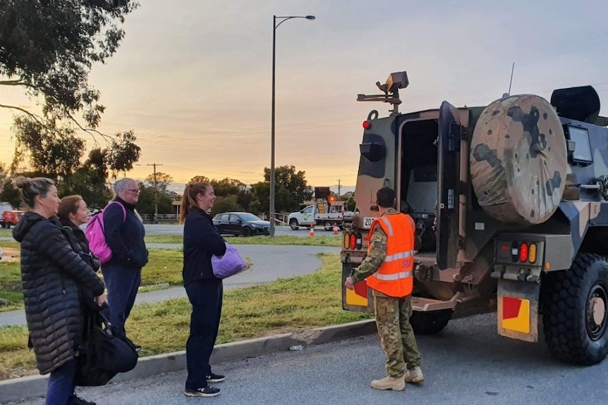 people standing next to an army vehicle