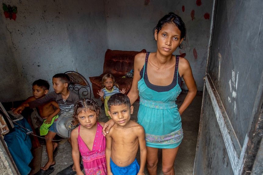 A young woman standing in a doorway surrounded by small children