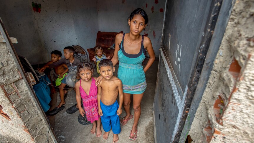 A young woman standing in a doorway surrounded by small children