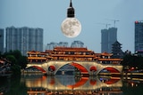 A moon, which replaces the globe in a light globe, hangs over Chengdu's cityscape.