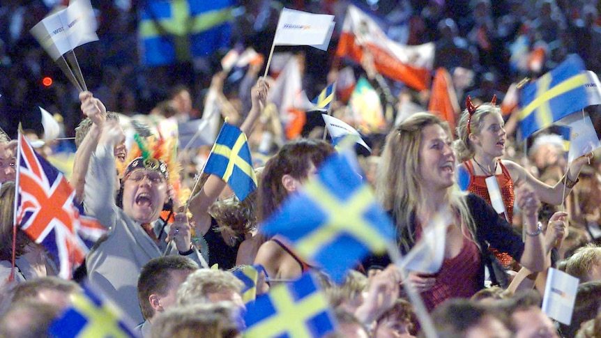 A cheering crowd wave mainly Swedish flags in the audience at the 2000 Eurovision Song Contest.