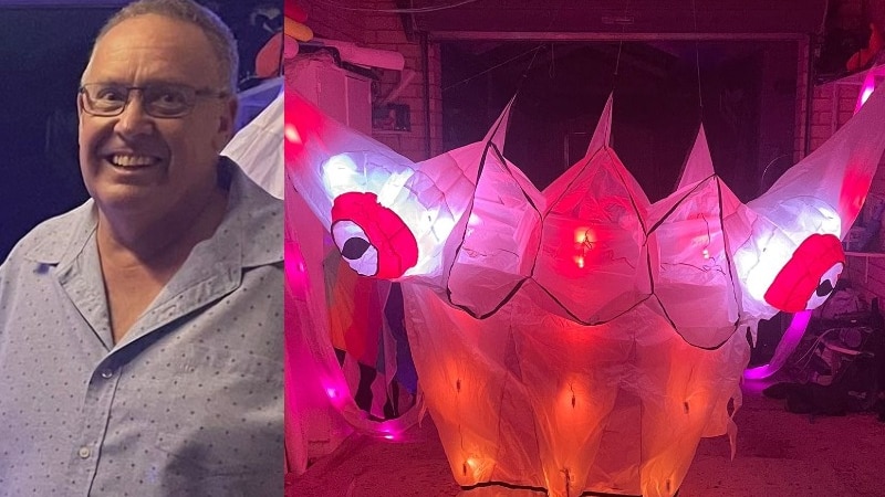smiling man in spectacles and a large kite that looks like a sea creature illuminated in red light