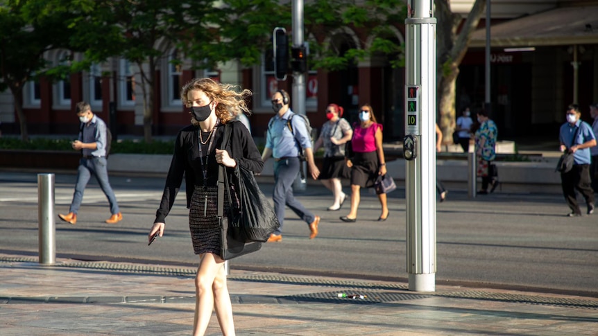 People cross a road wearing masks.