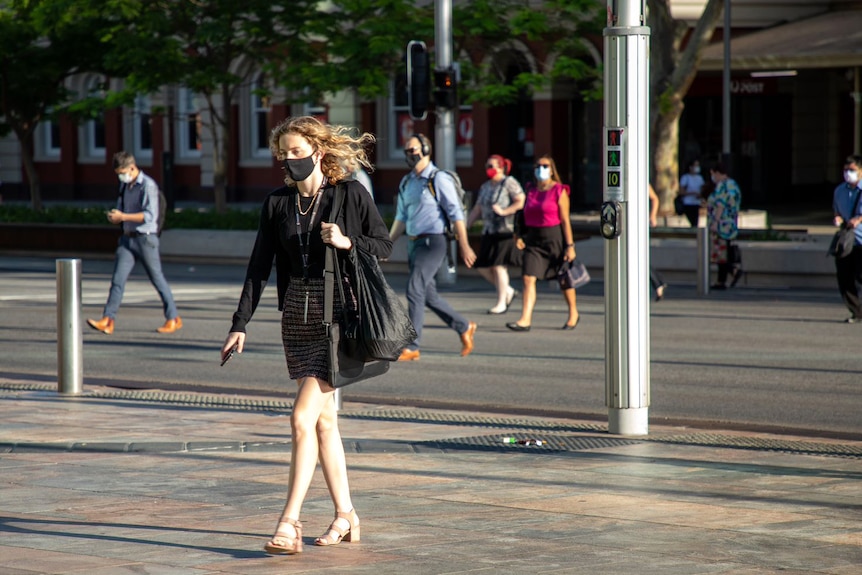 People cross a road wearing masks.