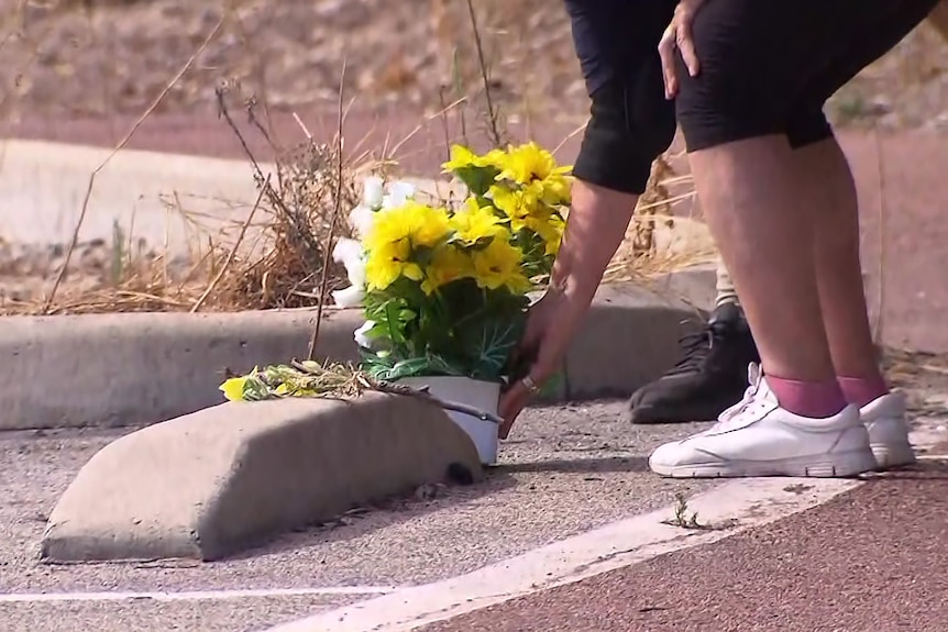 A close-up shot of yellow flowers being laid on the ground in a car park.