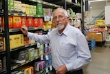 An older man in uniform tends to the shelves in a supermarket.