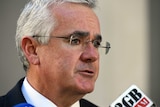Independent MP Andrew Wilkie speaks into a microphone. He has a concerned look on his face.