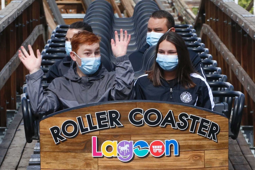 People in face masks on a roller coaster.