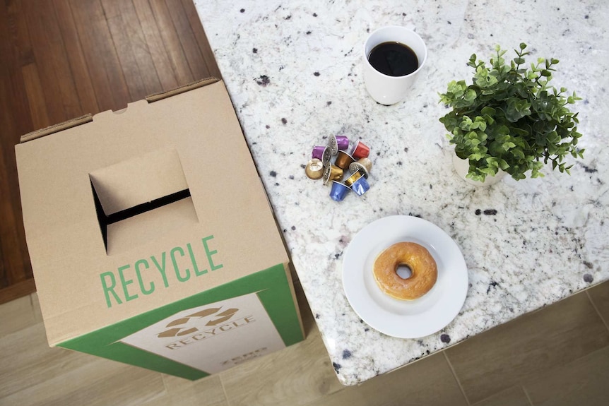 Coffee pods sit on a table next to a recycling bin