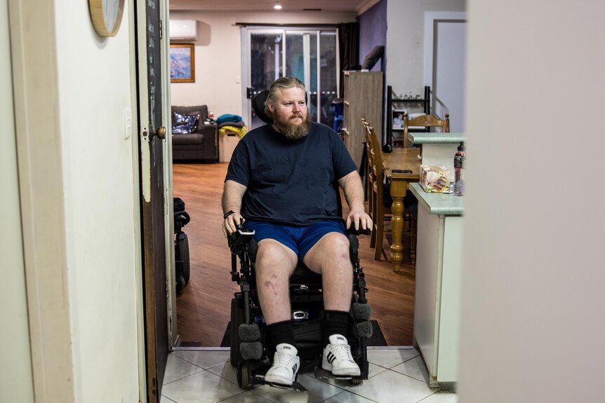 A paraplegic man in an electric wheelchair at his home.  