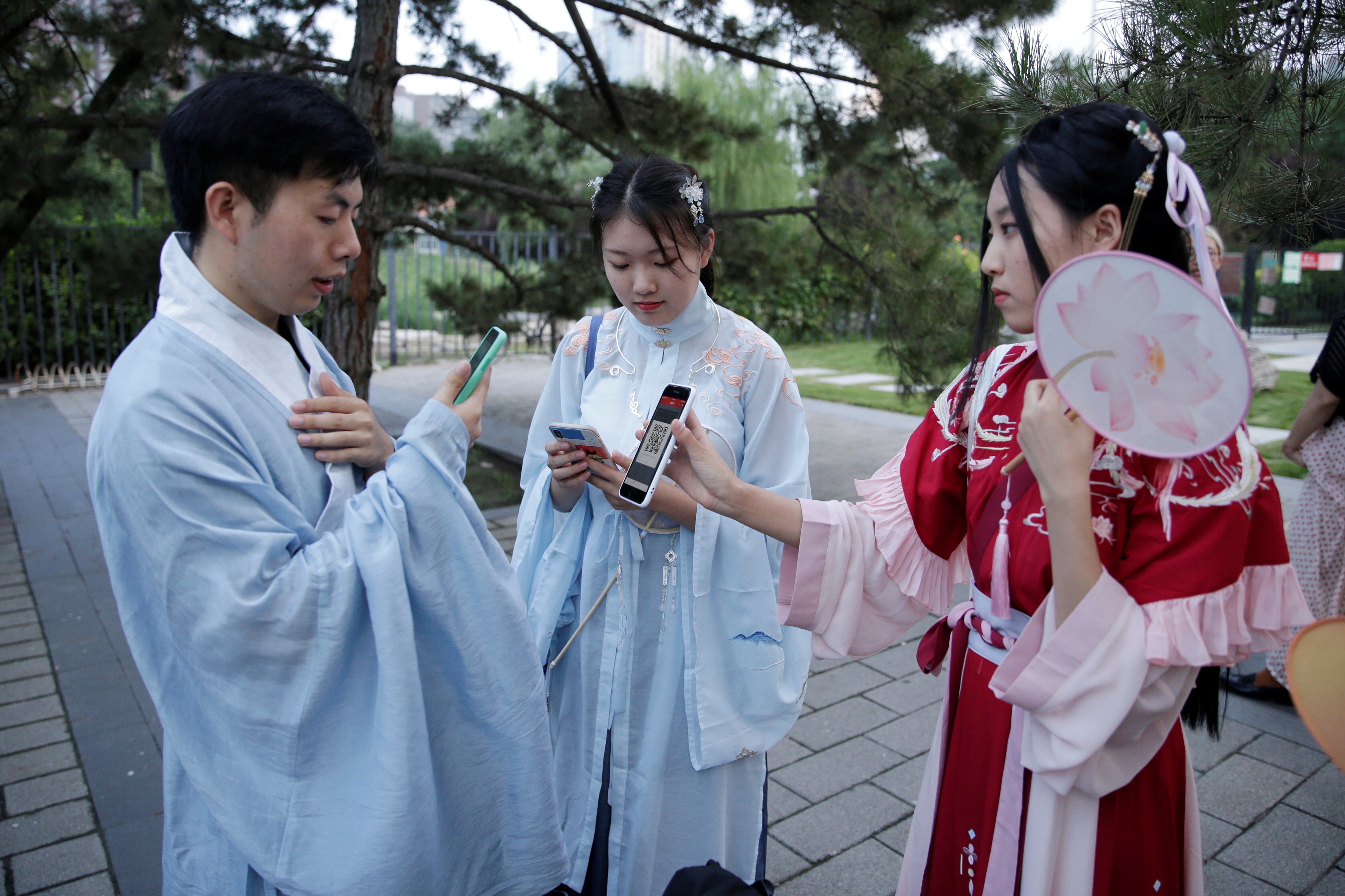 Young man in clothes "Hanfu"or Kanji clothing use mobile devices at events marking traditional Qixi festivals