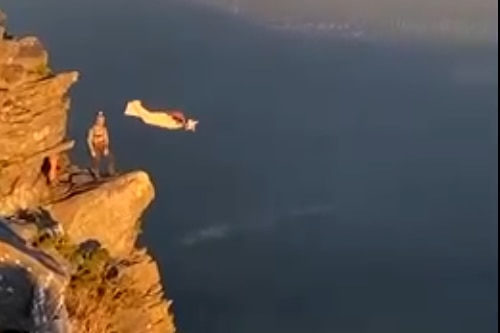 A person jumping off Bluff Knoll in a wing suit