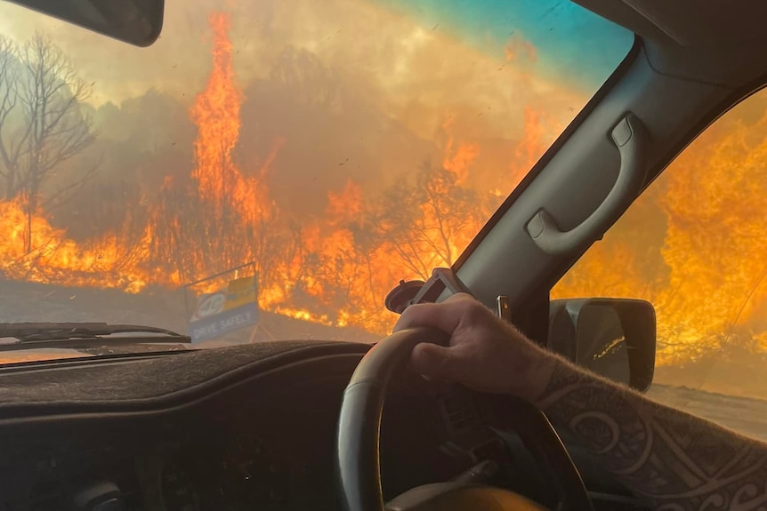 A man driving past a blaze.