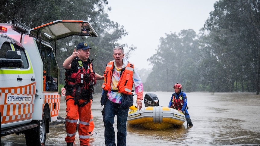 An elderly man walks out of floodwaters.