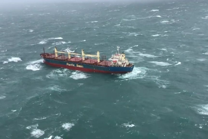 A large cargo ship being buffeted by waves in rough seas