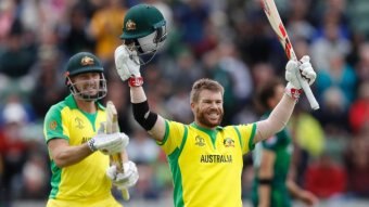 A batsman raises his helmet and bat in the air in celebration of an ODI century