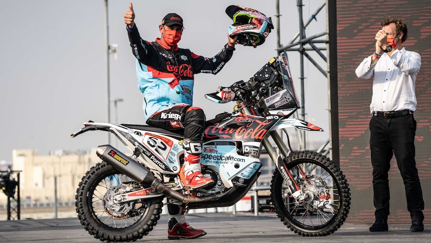 Man on podium with motorbike.