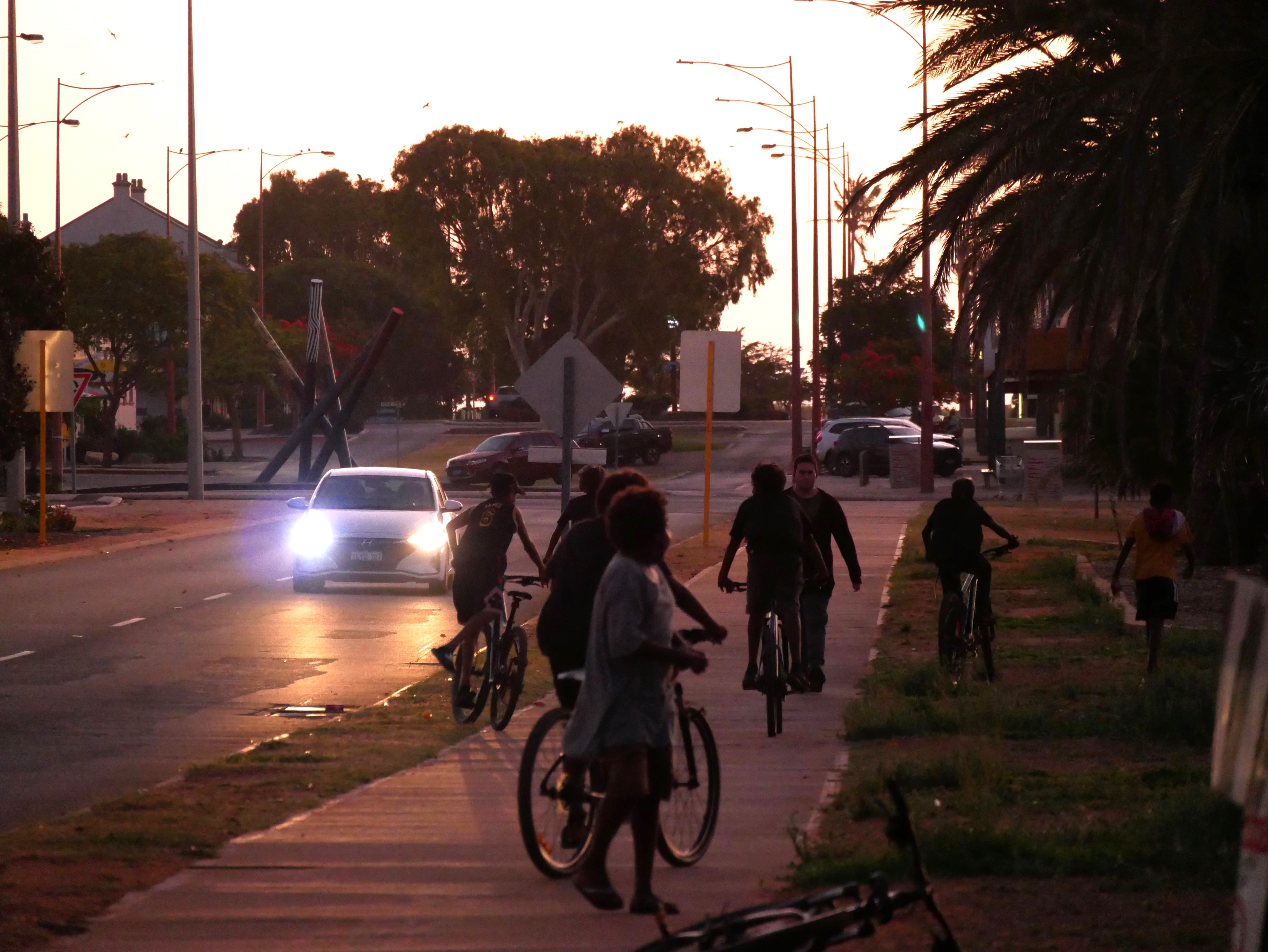 Carnarvon kids ride bicycles down a street.