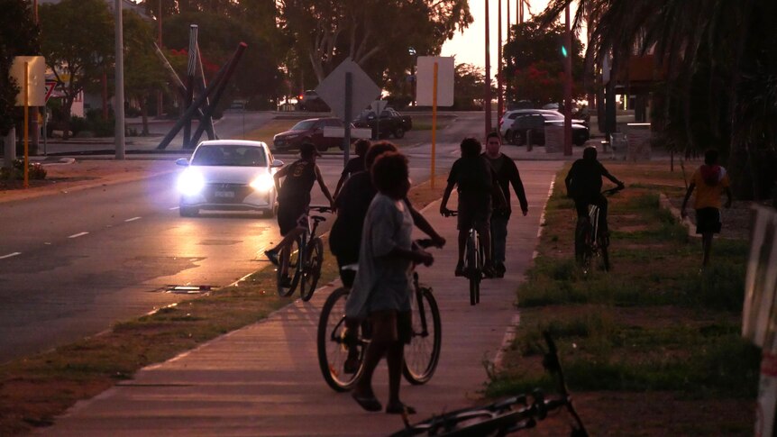 Carnarvon kids ride bicycles down a street.