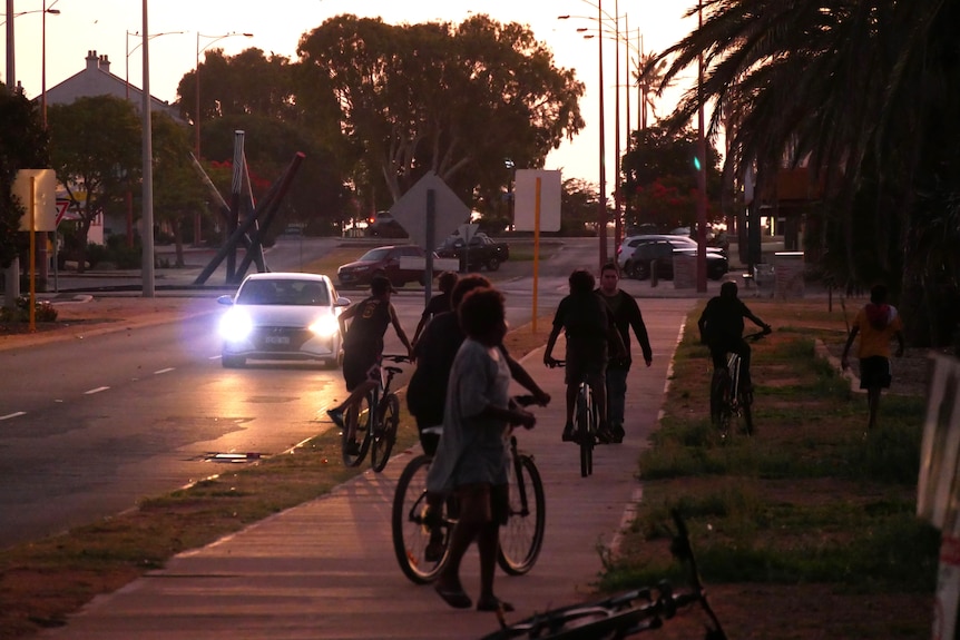Carnarvon kids ride bicycles down a street.