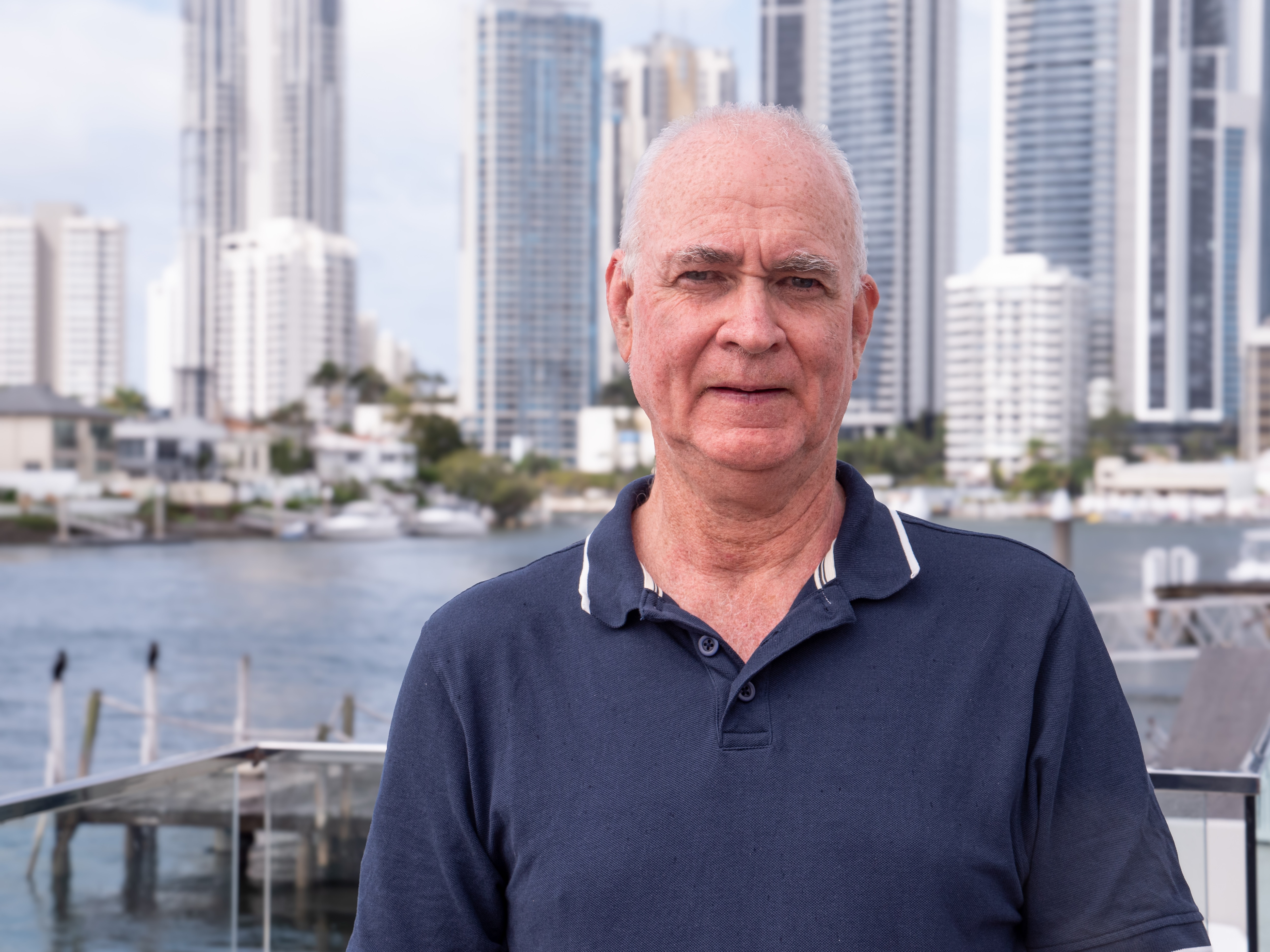 A man in a blue shirt staring at the camera with a canal behind him