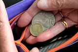 Hands put Australian coins into a wallet.