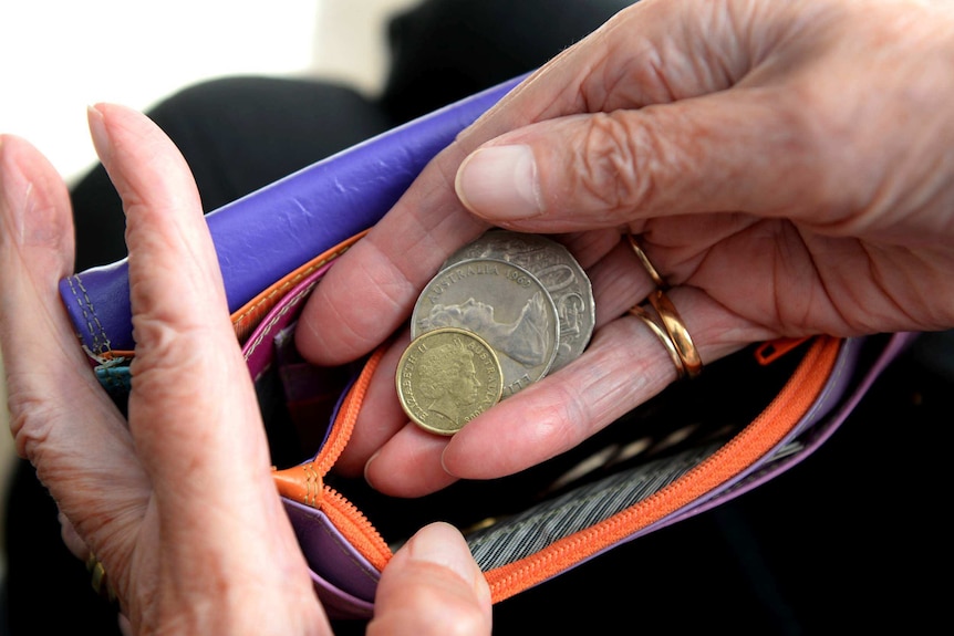 Hands put Australian coins into a wallet.