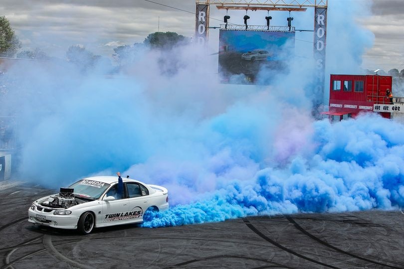 White car with lots of blue smoke coming from its tyres. 