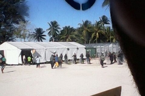 A man is taken away by security contractors in the detention centre on Manus Island
