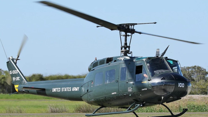 A green helicopter with US Army written on the tail. This helicopter has a large main rotor and a smaller vertical tail rotor.