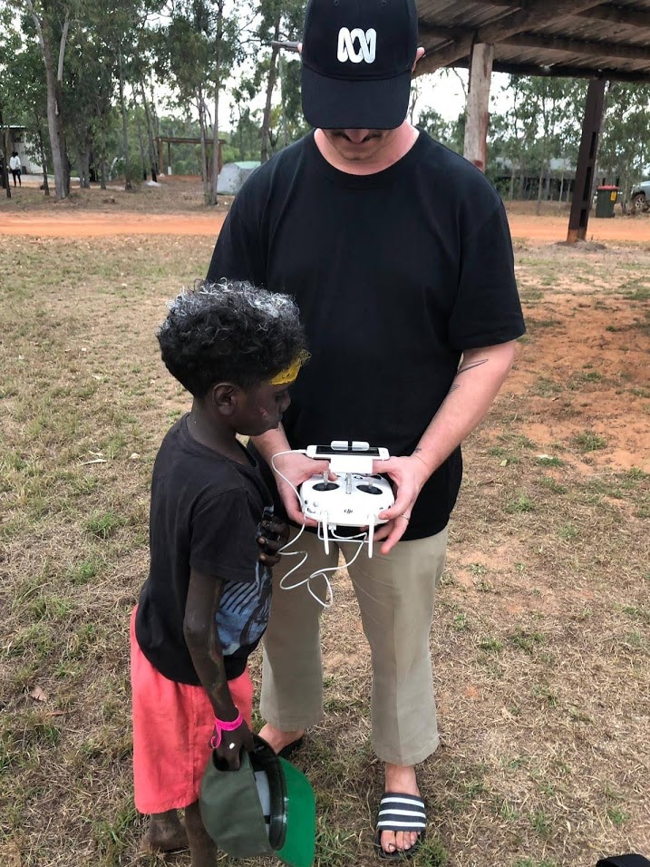 Man holding drone operating device showing young boy how it works.