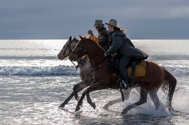 Two people galloping beside each other on horseback