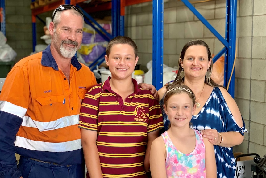 One of the first families to receive a 3D printed recycled plastic prosthetic hand stand in the warehouse where it will be made