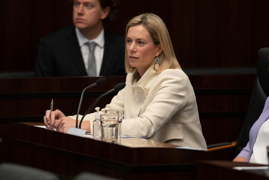 Rebecca White sits in parliament and listens to someone in question time while holding a pen.