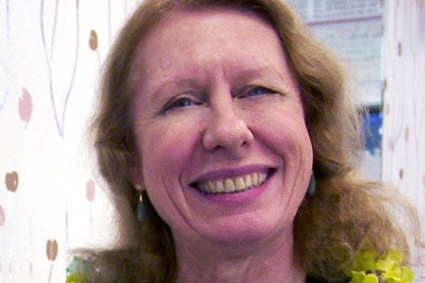 Headshot van Meda Chesney-Lind met kastanjebruin haar, grote glimlach en gele ketting om haar nek.