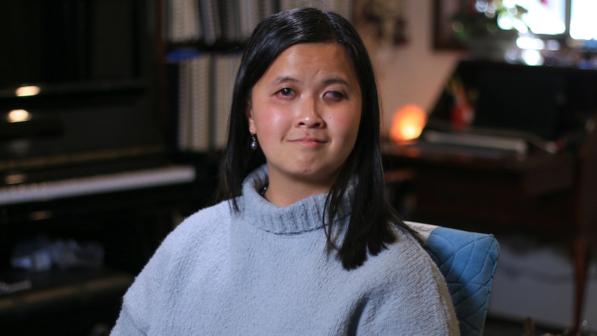 Ria Andriani wears a pale blue jumper, facing the camera in a portrait taken inside her home.