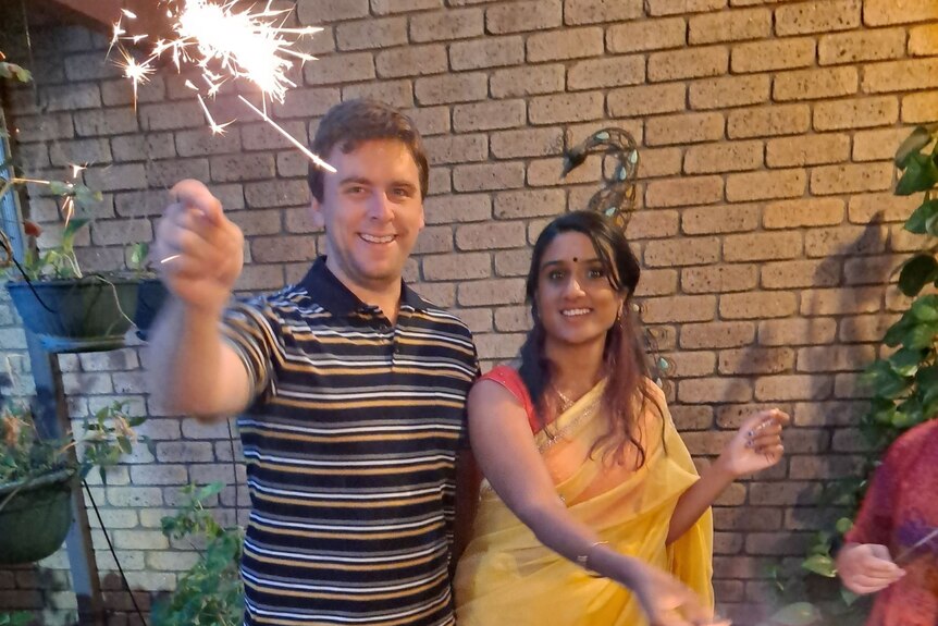 Vidya Rajan wearing a saree and her partner Scott Limbrick hold sparklers while celebrating Diwali.