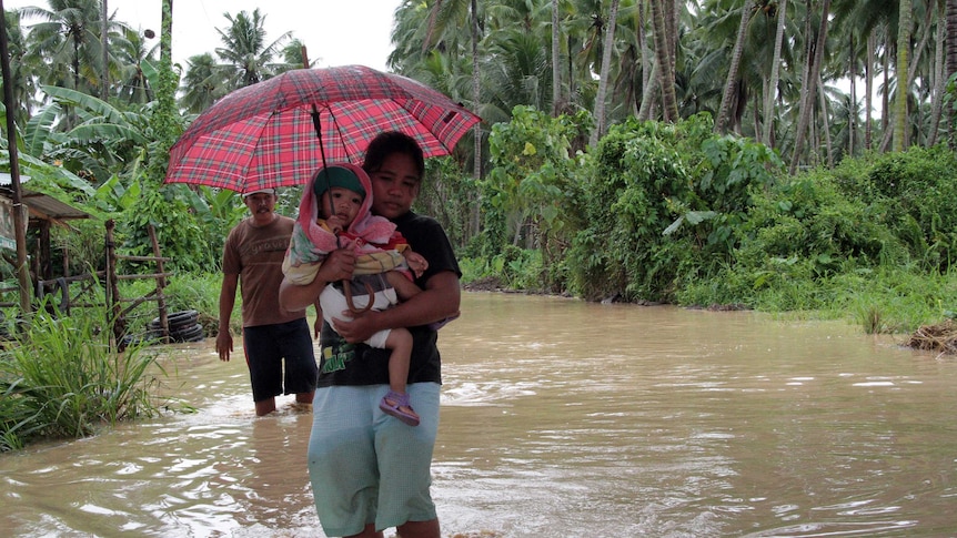 Woman walks through floods in the wake of Typhoon Bopha