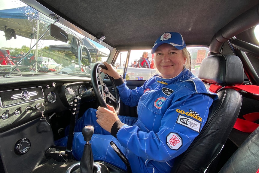 Sarah fry sits in the drivers seat of her race car wearing blue protective jumpsuit