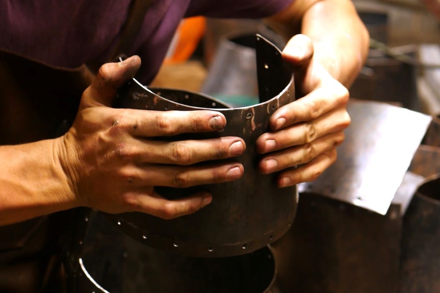 A man constructs a medieval helmet.