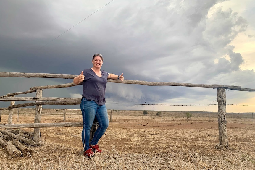 Woman standing in front of storm front and wooden fence