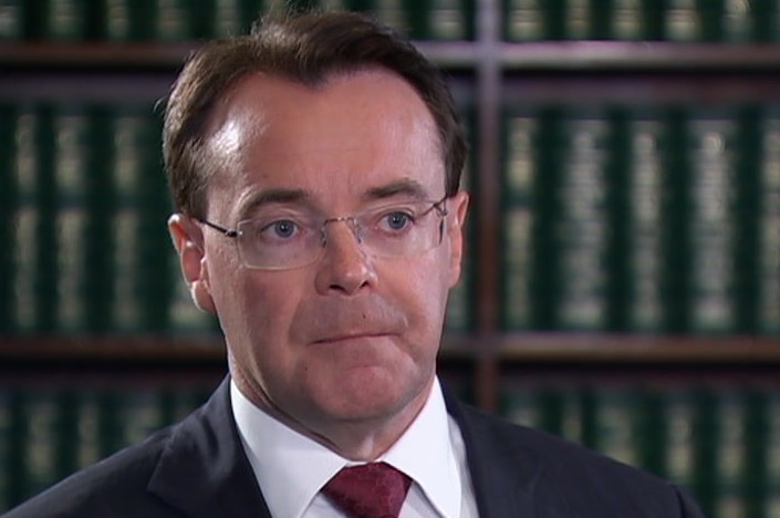 Michael O'Brien is dressed in suit and sitting in front of a bookshelf as he gives a one-on-one interview.