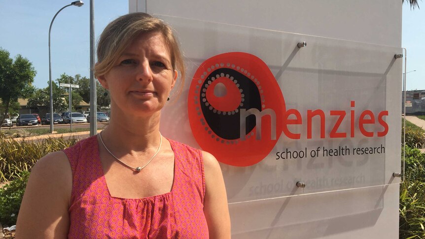 Marita Hefler stands in front of a Menzies School of Health Research sign.