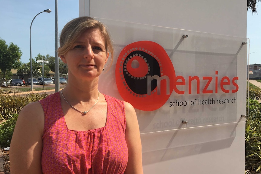 Marita Hefler stands in front of a Menzies School of Health Research sign.