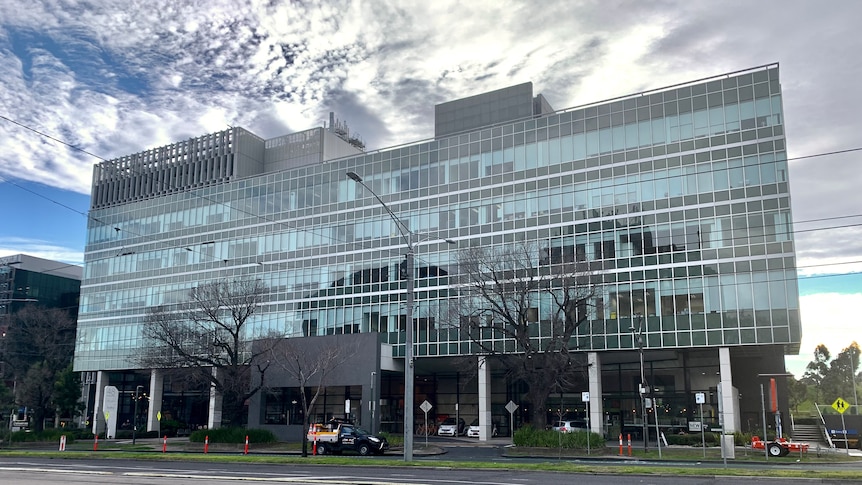 A large multi-storey medical building, viewed from across Flemington Road on a sunny winter day.