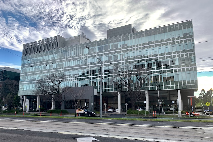 A large multi-storey medical building, viewed from across Flemington Road on a sunny winter day.