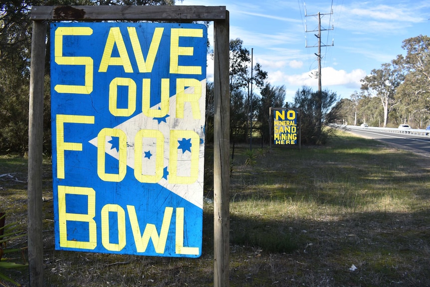 Two signs along a highway which carry anti-mining slogans.