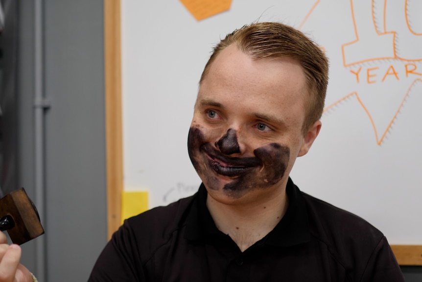 Young adult man with autism when stamp ink covering his face.