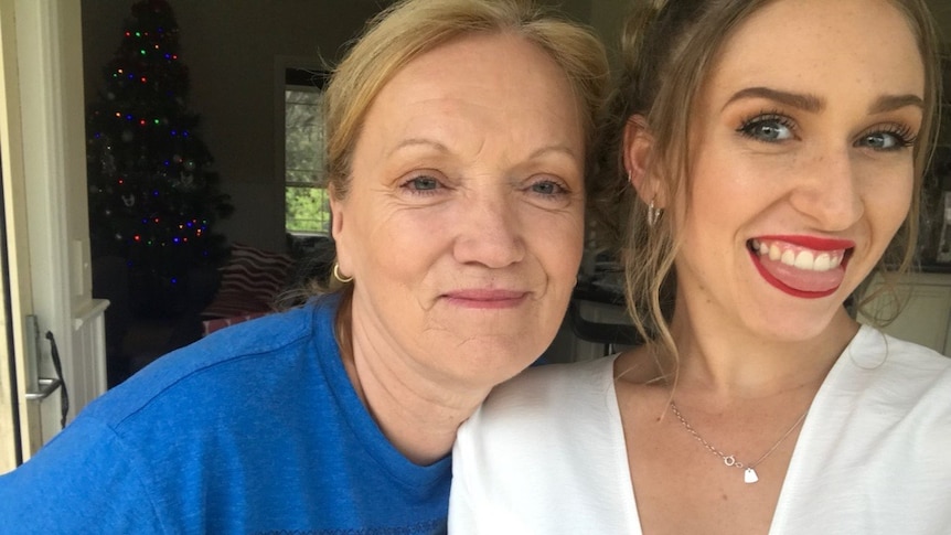 A young woman with red lipstick smiles while hugging her grandmother