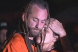 Murder accused Sara Connor and David Taylor embrace during a crime reconstruction, surrounded by Bali police officials and media